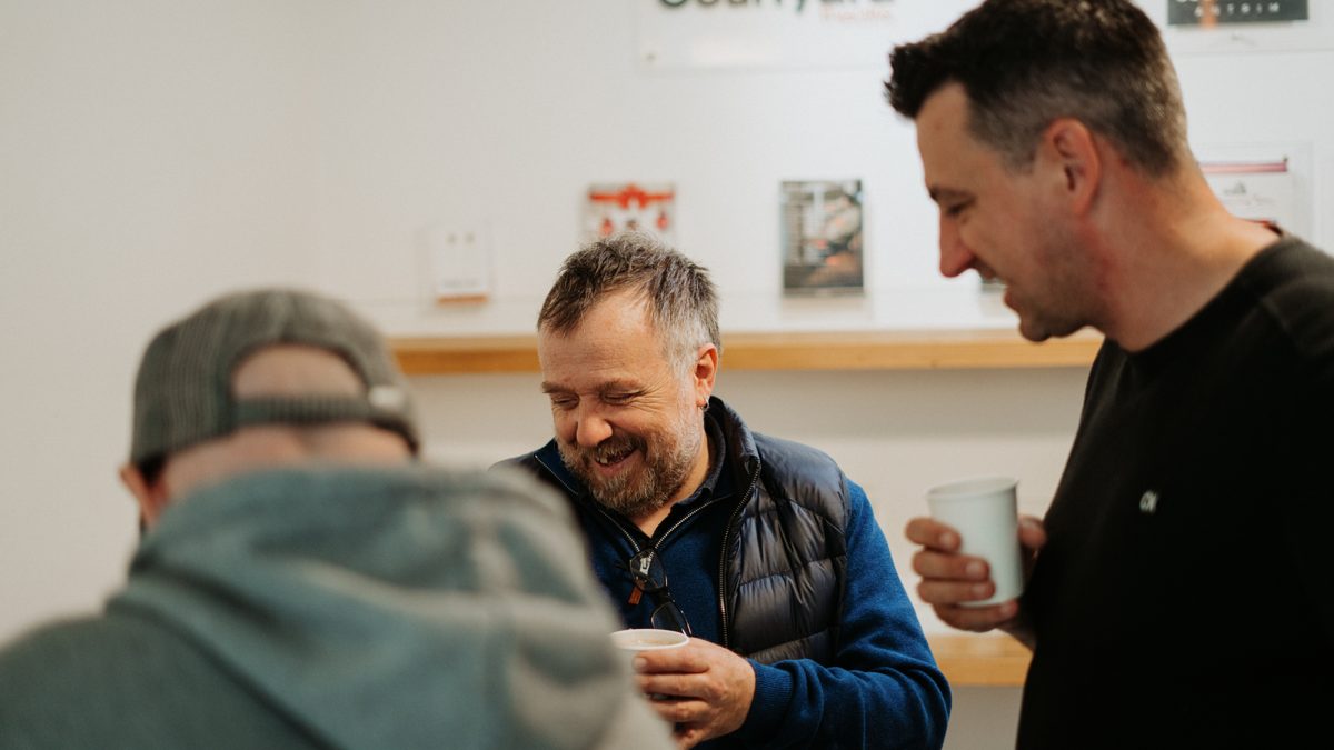 Friends laughing together over coffee in the lobby after a service