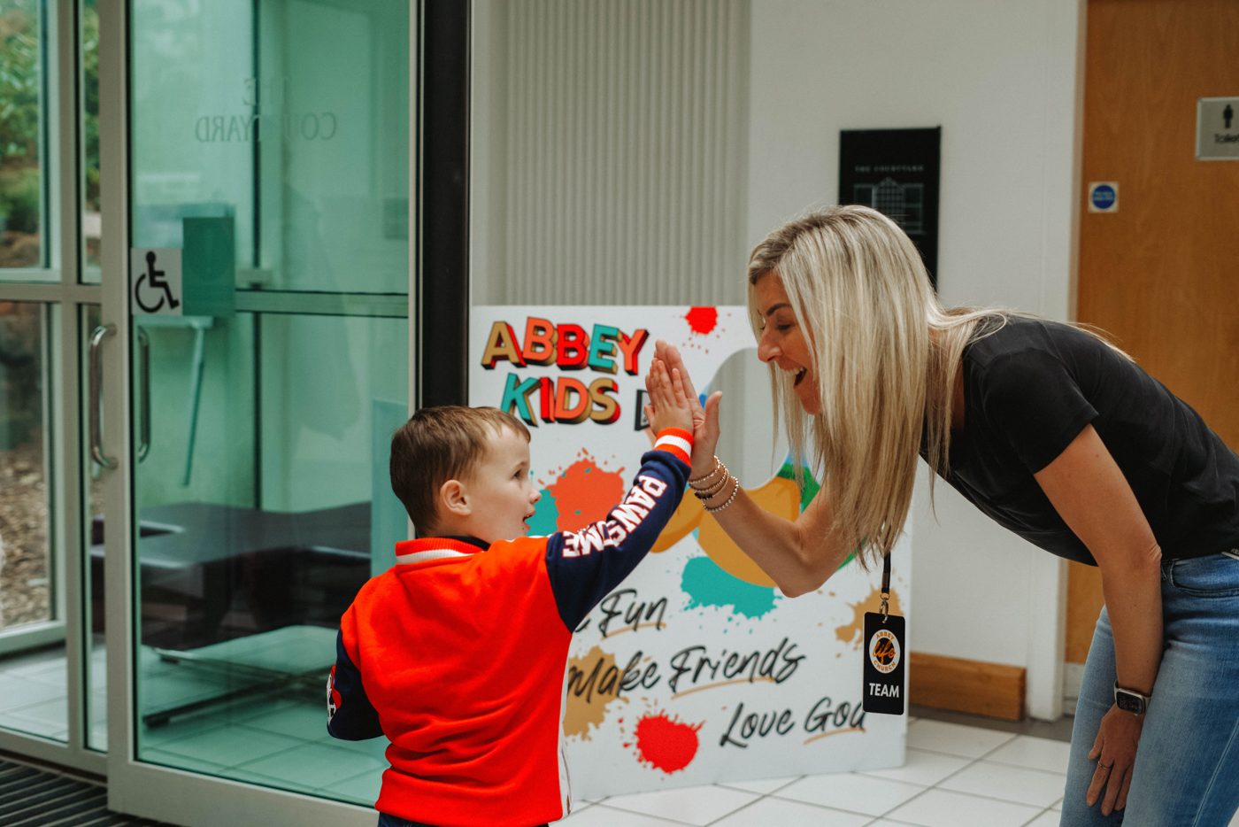 A leader high-fiving a child at the kids check-in